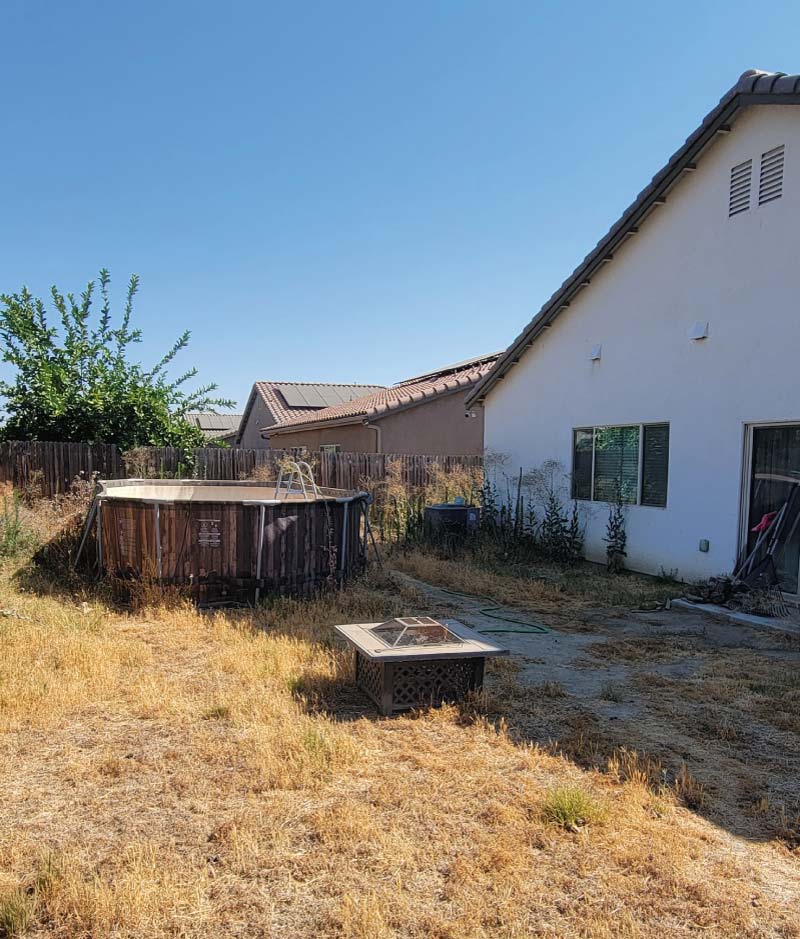 A cluttered backyard with an old above-ground swimming pool and overgrown brush, illustrating a property in need of a cleanout